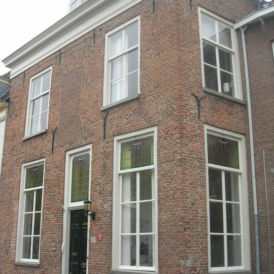 Woonhuis met rechte kroonlijst. 19e-eeuws voorkomen. In de vooruitspringende hoek een spiongat