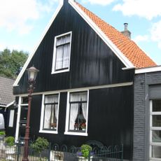 Houten dijkhuis met tuitgevel uit 19de eeuw, voordeur uit 18de eeuw