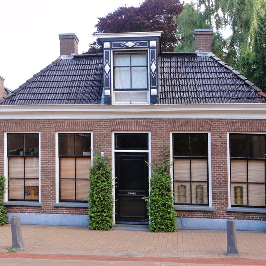 Landelijk pand zonder verdieping met zesruitsvensters onder omgaand zadeldak met dakkapel en vier hoekschoorstenen