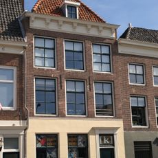 Huis met lijstgevel. Lijstfries voorzien van consoles. Dakkapel. Moderne winkelpui