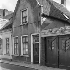 Eenvoudig dorpshuis met zadeldak en topgevel, verbonden met het dwarse zadeldak van nr