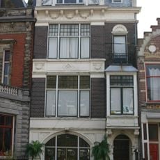 Herenhuis is in een donkerrode baksteen over drie bouwlagen opgetrokken op een rechthoekige plattegrond onder een afgeknot zadeldak met leien in Rijndekkin