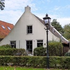 Pand met zesruitsvensters onder zadeldak tegen gewitte puntgevel met topvenster terzijde van het rookkanaal