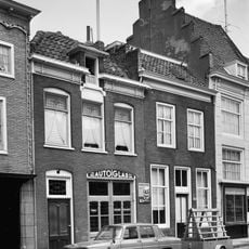 Pand, blijkens de afgeknotte trapgevel links. Goed bewaarde lijstgevel uit het midden van de 19e eeuw met zesruitsschuiframen. Het dak is verminkt