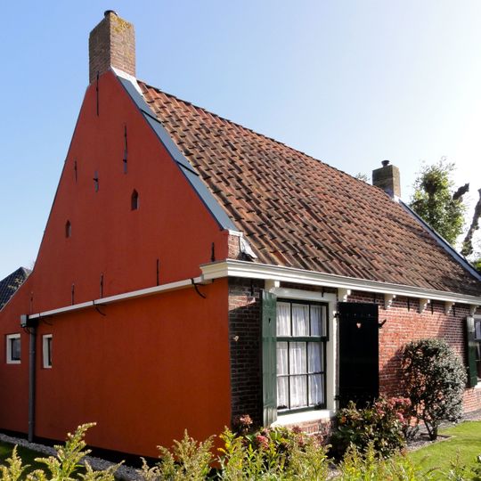 Visserswoning onder met rode pannen belegd zadeldak tussen topgevels met schoorstenen