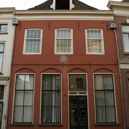 Huis met lijstgevel met gepleisterde pui, gevelsteen en dakkapel