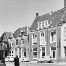 Pand met verdieping en hoog zadeldak, evenwijdig aan de markt tussen puntgevels gewijzigde trapgevels