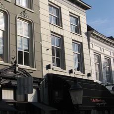 Huis met gebosseerd gepleisterde lijstgevel, kroonlijst op kleine voluutvormige consoles