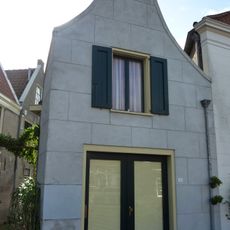 Pand met gepleisterde klokgevel en schuur