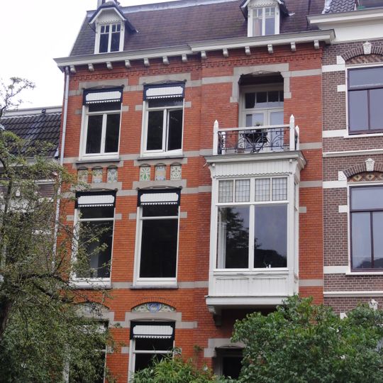Herenhuis met beneden- en bovenwoning en hek, gebouwd in overgangsarchitectuur met invloeden van de art nouveau in detaillering en materiaalgebruik