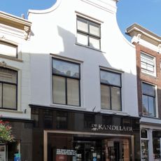 Pand met tuitgevel, afgedekt door lijst, gepleisterd. Pui en ramen modern