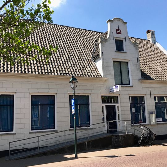 Dwarsgedekt pand aan een zijde met topgevel opgehaald, top met aanzetkrullen en gevelsteen