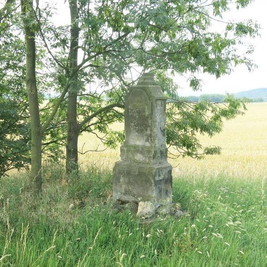 Podstavec s ulomeným kamenným křížem u silnice 28 východně od Rané