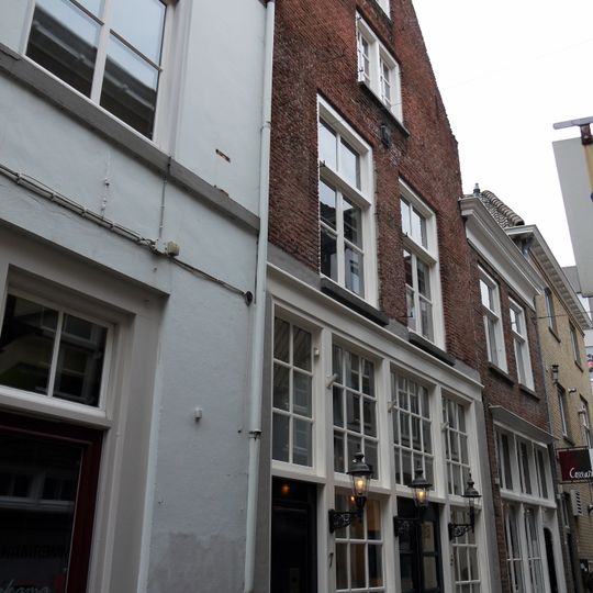 Huis onder zadeldak en met topgevel waarin schuiframen en houten pui met witte roedenverdeling