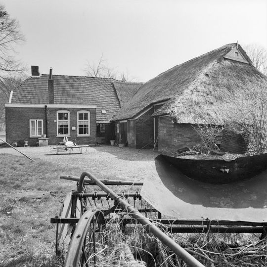 Boerderij met woondeel onder pannen wolfsdak en bedrijfsdeel met zijbaander onder aan de voorzijde afgewolfd rieten schilddak