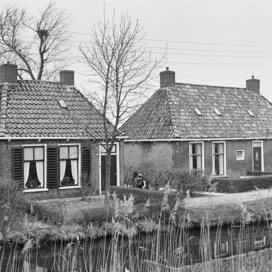 Landelijk pand met goot op klossen onder schilddak met twee hoekschoorstenen