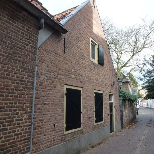 Behoort tot de woning Dekanijstraat 2, is daarvan een vleugel in het L-vormig complex. Zadeldak van rode pannen.