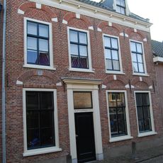 Huis met in de gevel geblokte ontlastingsbogen en in de verdieping schuiframen