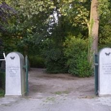 Noordelijke zij-ingang bestaande uit twee hardstenen pijlers met daartusen dubbele gegalvaniseerde draaihekken