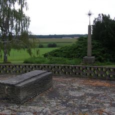 Sloup s plastikou u křižovatky před hřbitovem v Sukoradech