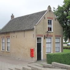 In oorsprong ten behoeve van de naastgelegen korenmolen 'de Hoop' gebouwde molenaarswoning, bestaande uit een verdiepingloos pand onder met blauwe pannen gedekt zadeldak tussen tuitgevels.