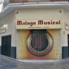 Mural en la persiana de cierre de la tienda de instrumentos musicales Málaga Musical representando la boca y la roseta de una guitarra española.