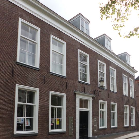 Voormalige Stadsdoelen. Statig breed gebouw, lijstgevel. Dubbele topgevel terzijde met zakgoot en uitgebouwde vleugel