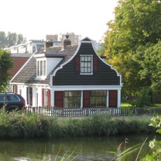 Houten molenaarshuis met klokgevel (uit- en ingezwenkt voorschot) uit 19de eeuw, ernaast molen d' Armiraal