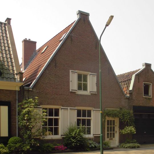 Pand met forse met vlechtingen gemetselde tuitgevel aan de straat