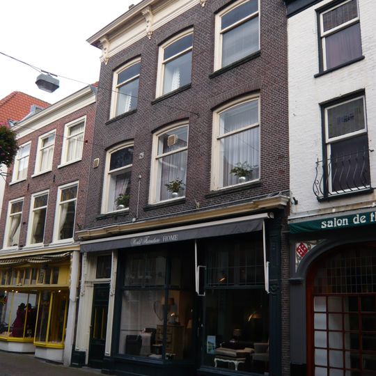 Pand met rechte kroonlijst rustend op consoles. Beneden verbouwd