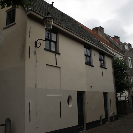 Witgepleisterde eenvoudige woning met rechte kroonlijst en zadeldak, deels uit 16e en 17e eeuw