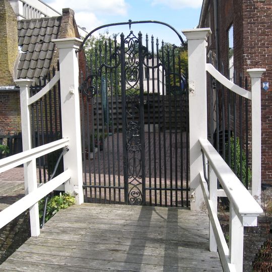 Hek naar het erf van het bouwhuis met bakstenen keermuren