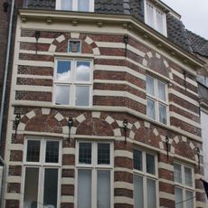 Hoekpand met gevels van bakstenen afgewisseld door zandstenen banden en met sierankers