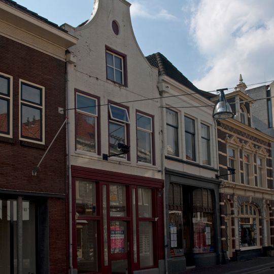 Pand met klokgevel waaraan fronton en aanzetvoluten ontbreken en met jongere onderpui