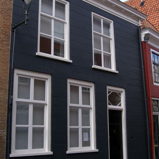 Zeer eenvoudig huis met gebosseerde gepleisterde lijstgevel