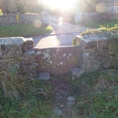 Stone stile and attached wall about 5 1/2 metres long, adjoining on east of wall of Quenington House