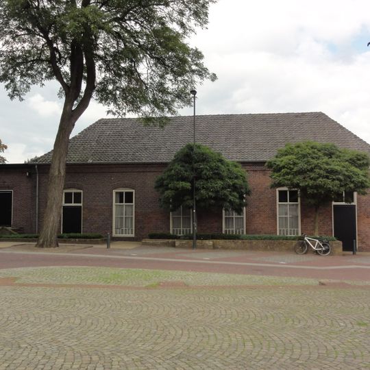 Voormalig schoolgebouw. Rechthoekig pand met getoogde vensters en langgerekt pannen schilddak. Geprofileerde, bakstenen waterlijst onder de dakvoet. Aan de westzijde later verlengd