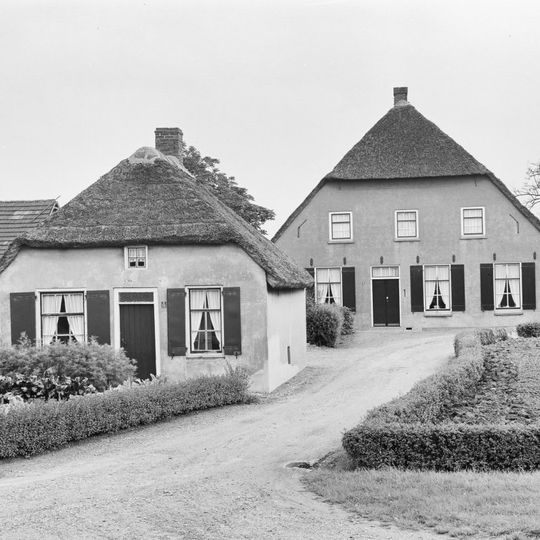Grote boerderij met gepleisterd woongedeelte, waarin vensters met luiken en zes- en negenruitsschuiframen