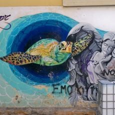 Grafiti mural representando a una mujer alada junto a una tortuga marina.