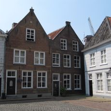 Huis met tuitgevel met vlechtingen en versierde top, achtergevel met schilddak aan de postweg