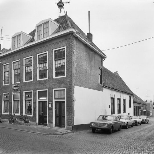 Vijf vensters brede lijstgevel met gesneden deurkalven, verknoeide ramen en gootlijst