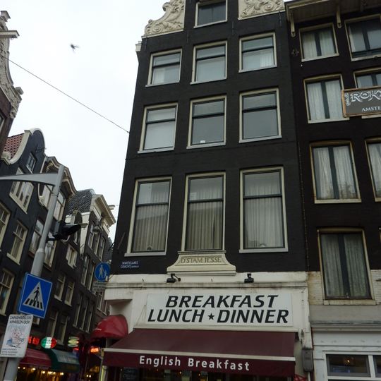 Hoekhuis met halsgevel met zware vleugelstukken van bijzonder ontwerp en een gevelsteen