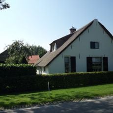 Boerderij, gepleisterd bakstenen gebouw onder rieten zadeldak met topgevel aan de voorzijde en afgewolfd aan de achterkant