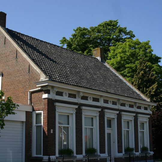 Woonhuis, halfvrijstaand aan de doorgaande weg. Het huis heeft kenmerken van Eclecticisme