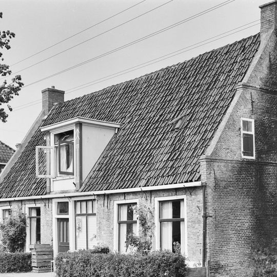 Pand onder zadeldak tussen twee topgevels met waterlijsten, beitelingen langs de zijden en ieder twee kleine lichtopeningen met luiken