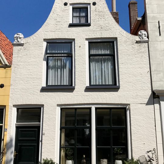 Pand onder zadeldak tegen klokgevel met aanzetkrullen en bekronende verhoogde lijst