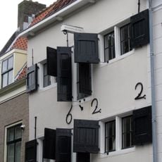 Pakhuis in lichte kleur gepleisterd van drie bouwlagen onder een schilddak