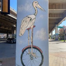 A mural of a flamingo riding a unicycle