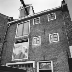 Drie verdiepingen hoog pand met tuitgevel met vlechtingen en staafankers