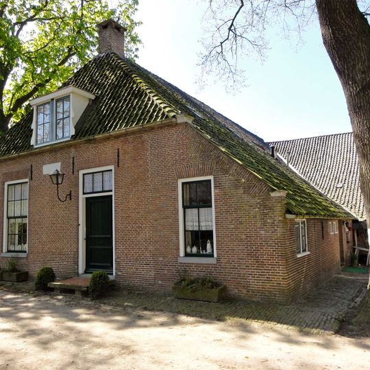 Boerderij. Op L-vormige plattegrond, met aangebouwde schuur, gedekt door een met zwarte pannen belegde kap